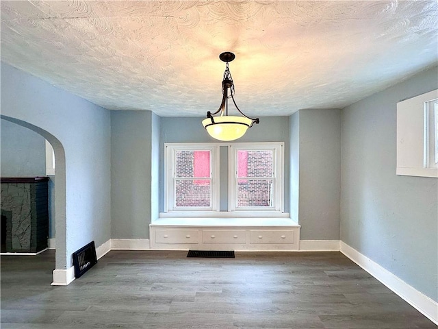 unfurnished dining area with dark hardwood / wood-style floors and a textured ceiling