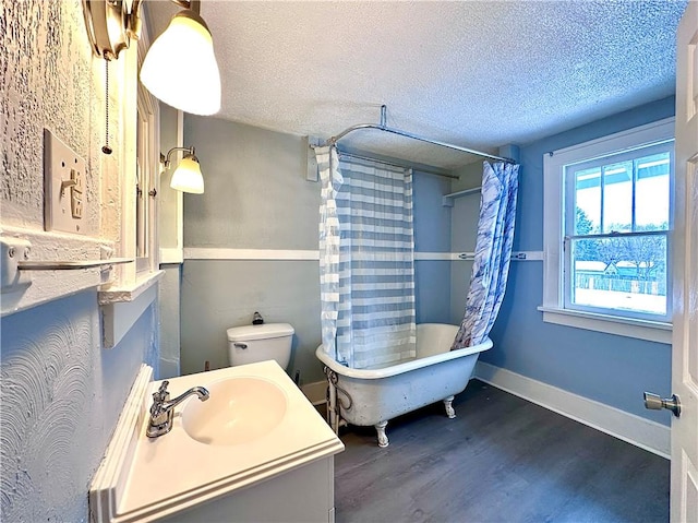 full bathroom with shower / tub combo, hardwood / wood-style floors, vanity, a textured ceiling, and toilet