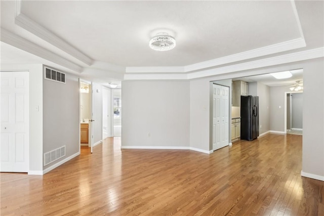 empty room featuring crown molding, hardwood / wood-style flooring, and a raised ceiling