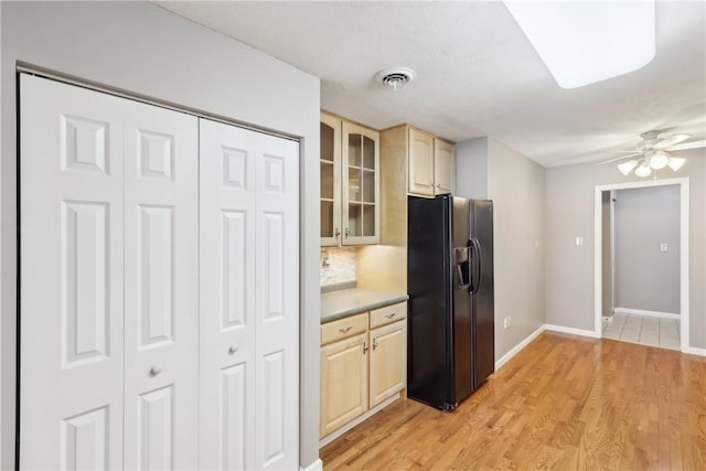 kitchen featuring ceiling fan, light hardwood / wood-style floors, decorative backsplash, light brown cabinetry, and black fridge with ice dispenser