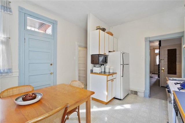 kitchen featuring white cabinetry, high end stainless steel range, and white fridge