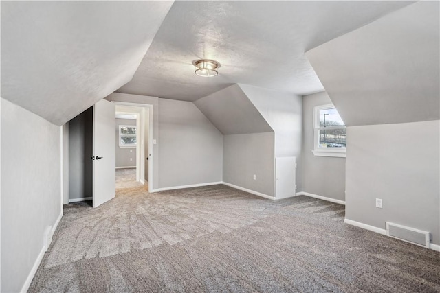 bonus room with lofted ceiling, a textured ceiling, and carpet