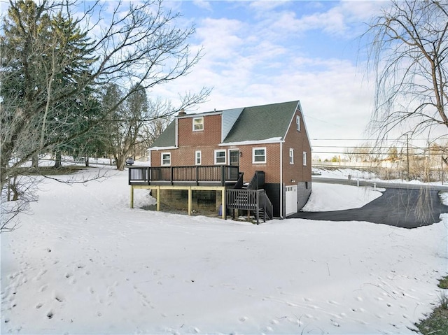 snow covered rear of property with a deck