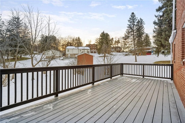 snow covered deck featuring a storage shed