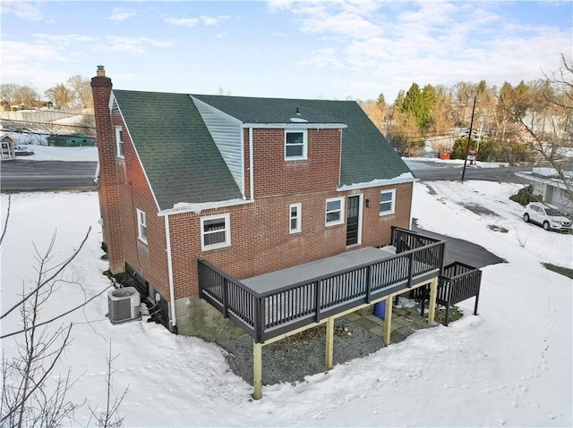 snow covered rear of property featuring central air condition unit and a deck