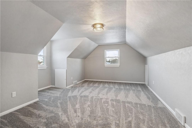 bonus room featuring lofted ceiling, a textured ceiling, and carpet flooring