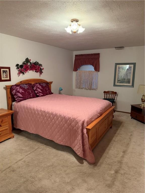 bedroom with light carpet and a textured ceiling