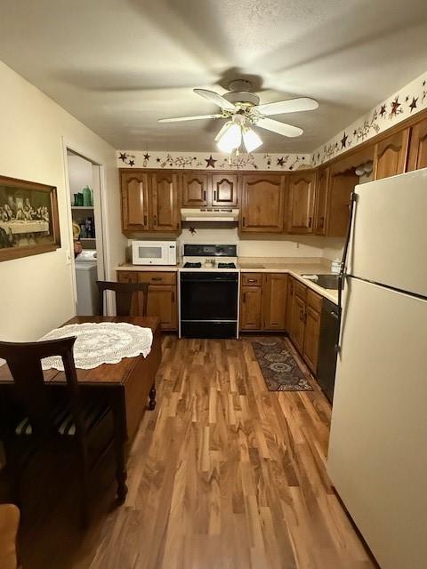 kitchen featuring dark wood-type flooring, sink, white appliances, ceiling fan, and washer / clothes dryer