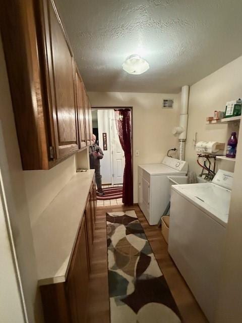 laundry room featuring separate washer and dryer, a textured ceiling, and light hardwood / wood-style flooring