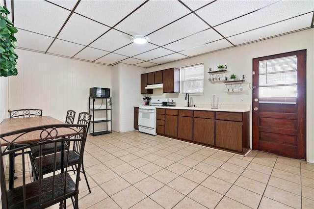 kitchen with white range with gas cooktop, light tile patterned floors, dark brown cabinets, and a drop ceiling