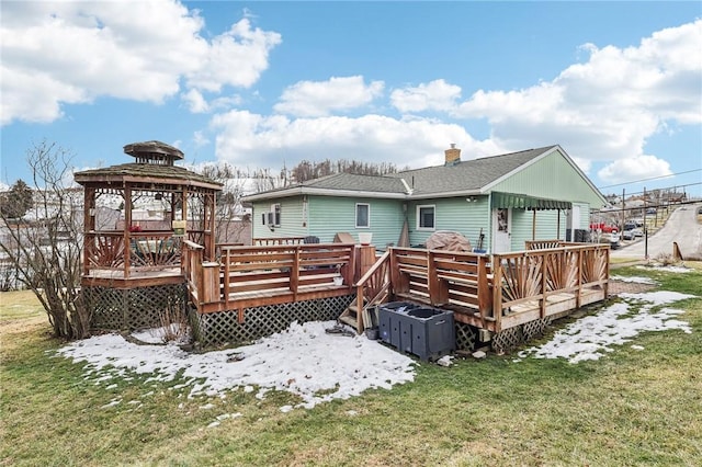 snow covered rear of property with a yard, a gazebo, and a wooden deck