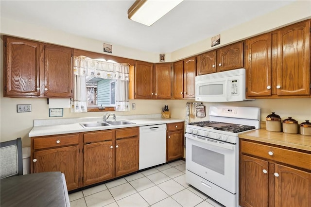 kitchen featuring sink, light tile patterned floors, and white appliances