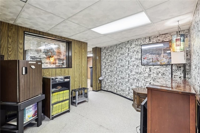 interior space with a paneled ceiling and wood walls