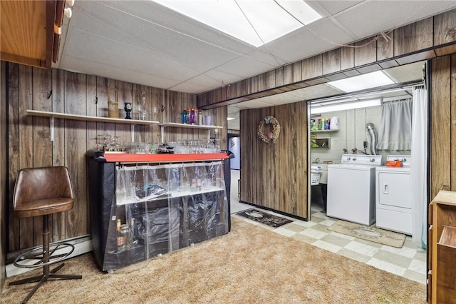 washroom with washing machine and dryer, bar area, and wood walls