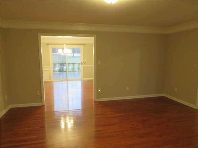 unfurnished room featuring crown molding, dark hardwood / wood-style floors, and a notable chandelier