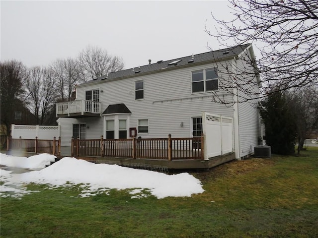 snow covered house featuring central AC and a lawn