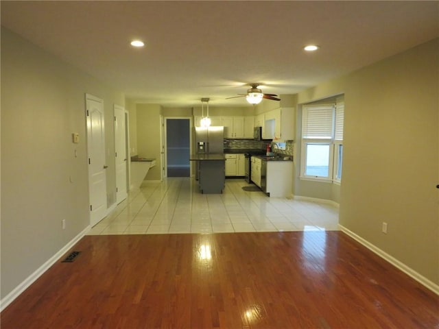 kitchen featuring a kitchen island, white cabinetry, decorative backsplash, hanging light fixtures, and stainless steel refrigerator with ice dispenser