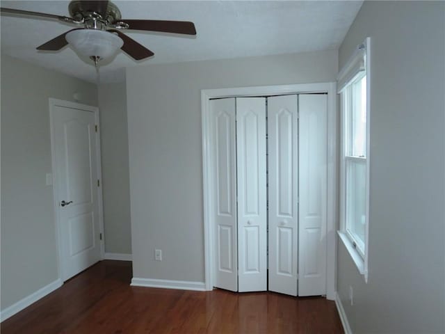 unfurnished bedroom with dark wood-type flooring, a closet, and ceiling fan