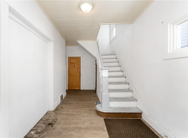 staircase featuring wood-type flooring and ornamental molding