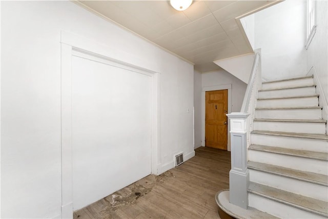 staircase featuring ornamental molding and hardwood / wood-style floors