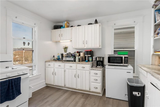 kitchen featuring refrigerator, a wealth of natural light, white cabinets, and white stove