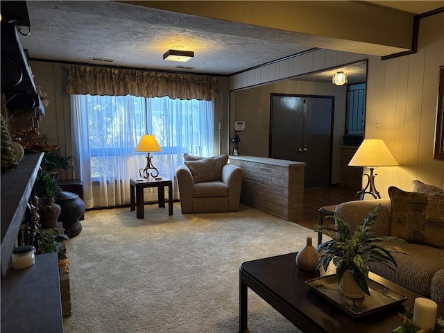 carpeted living area with wooden walls, visible vents, and a textured ceiling