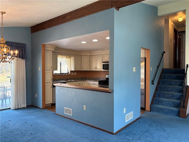 kitchen featuring visible vents, light colored carpet, appliances with stainless steel finishes, decorative light fixtures, and a sink