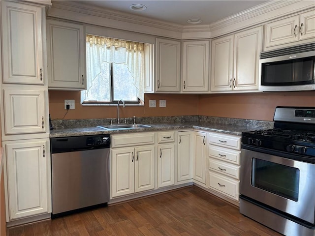 kitchen featuring stainless steel appliances, dark countertops, dark wood finished floors, and a sink