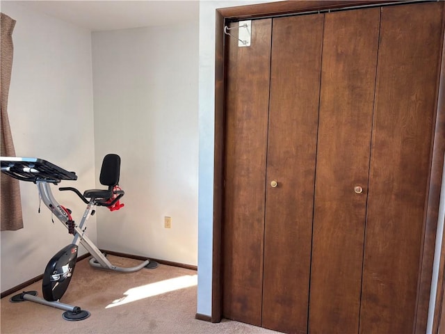 workout room featuring light carpet and baseboards