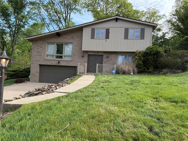 split level home featuring brick siding, a garage, driveway, and a front lawn