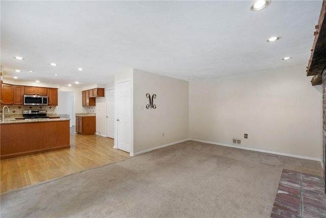 unfurnished living room featuring light colored carpet and sink