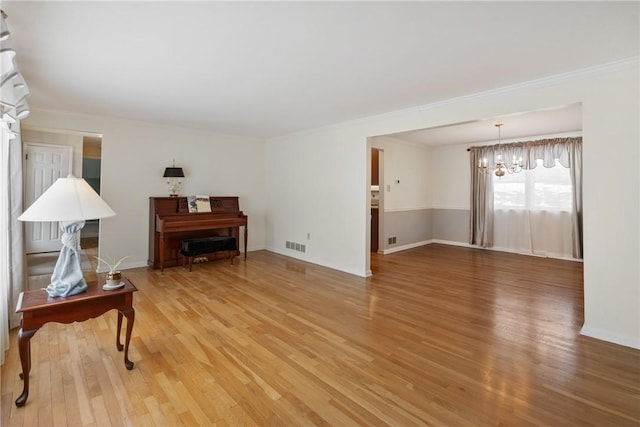 living room with an inviting chandelier, crown molding, and hardwood / wood-style flooring