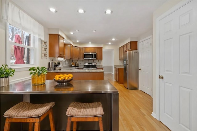 kitchen with appliances with stainless steel finishes, a kitchen bar, kitchen peninsula, and stainless steel counters