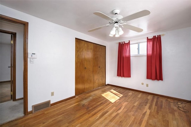 unfurnished bedroom featuring hardwood / wood-style floors, ceiling fan, and a closet