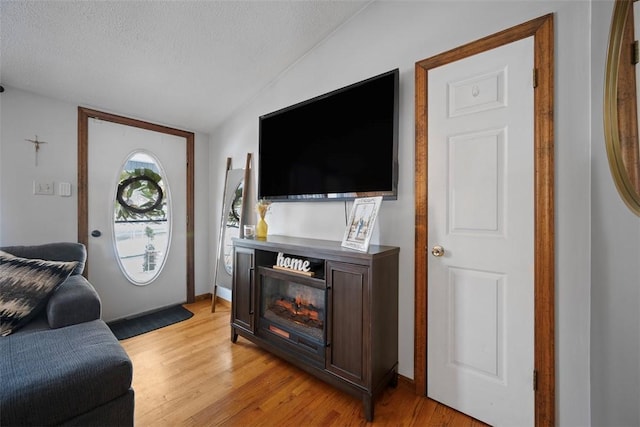 living room featuring lofted ceiling, a textured ceiling, and light hardwood / wood-style floors