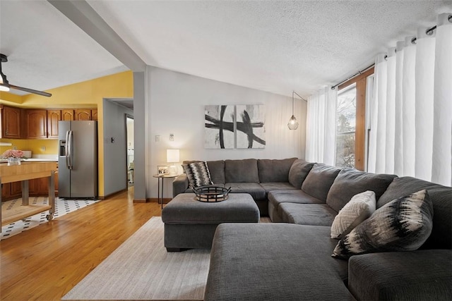 living room with lofted ceiling, light hardwood / wood-style flooring, and a textured ceiling