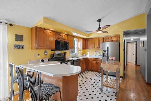 kitchen featuring appliances with stainless steel finishes, kitchen peninsula, sink, and a textured ceiling