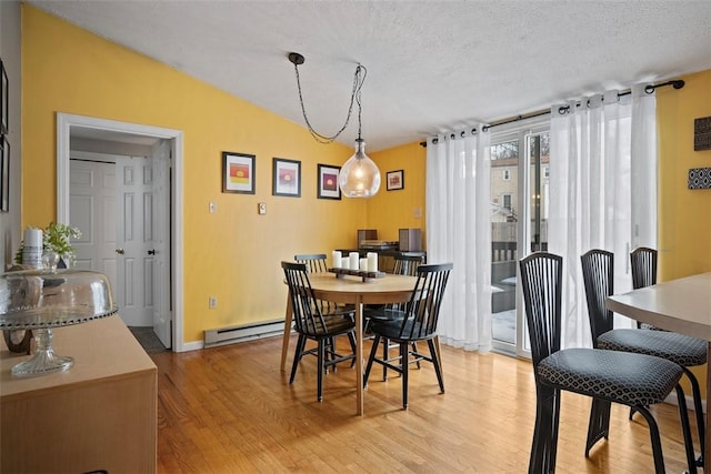 dining space featuring a baseboard radiator, a textured ceiling, and light wood-type flooring