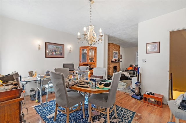 dining area featuring a fireplace, a notable chandelier, and light hardwood / wood-style flooring