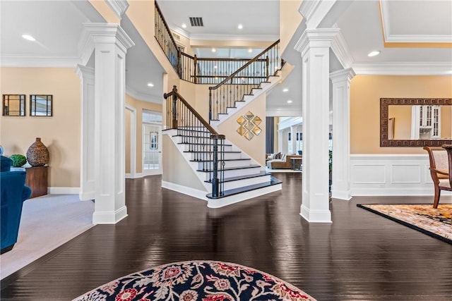 entrance foyer with dark wood-type flooring, ornamental molding, and ornate columns