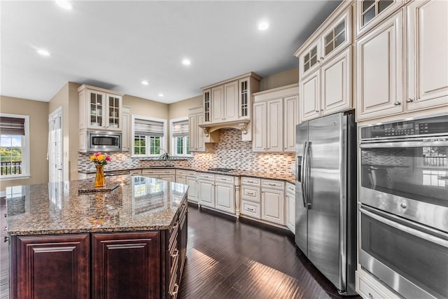 kitchen featuring plenty of natural light, light stone countertops, cream cabinetry, and appliances with stainless steel finishes