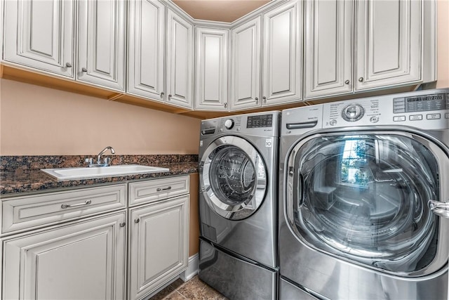 clothes washing area featuring cabinets, sink, and washer and clothes dryer