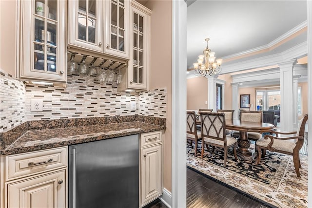 kitchen with stainless steel refrigerator, decorative columns, dark hardwood / wood-style floors, ornamental molding, and dark stone counters