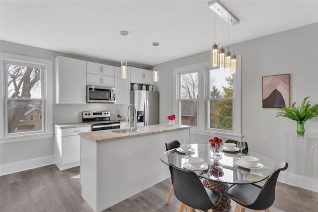 kitchen featuring sink, stainless steel appliances, an island with sink, and white cabinets