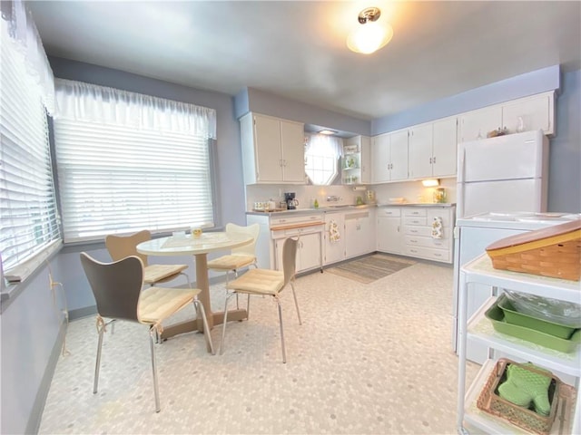 kitchen featuring white cabinetry, decorative backsplash, and white fridge