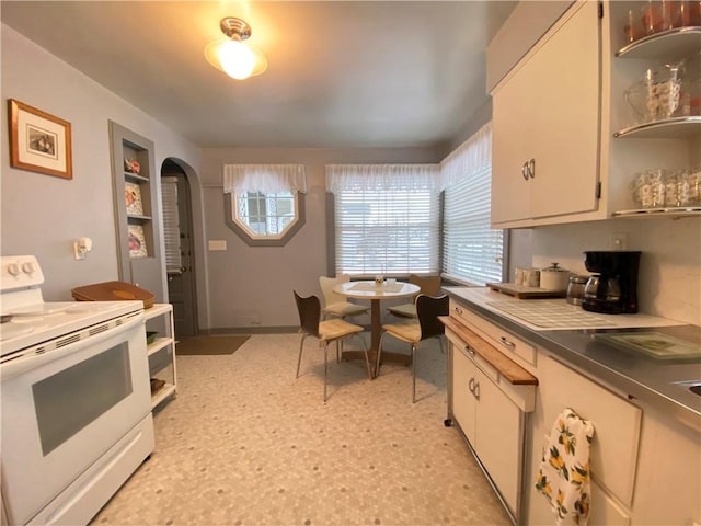 kitchen featuring a wealth of natural light, white cabinets, and white range with electric stovetop