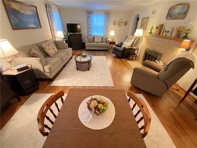 living room with hardwood / wood-style floors and a brick fireplace