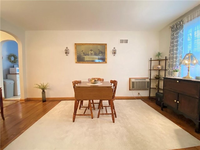 dining area featuring hardwood / wood-style flooring and a wall mounted air conditioner