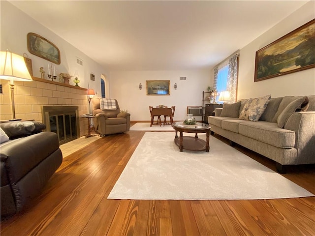 living room with hardwood / wood-style flooring and a brick fireplace