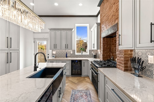 kitchen featuring range with gas stovetop, decorative light fixtures, wine cooler, light parquet flooring, and light stone countertops